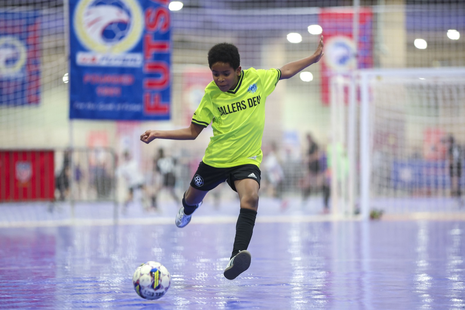 Youth futsal player striking the ball mid-shot at the US Futsal National Championship
